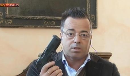 Il sindaco di Borgosesia ed eurodeputato della Lega Gianluca Buonanno in collegamento con SkyTg24 sul caso del pensionato che ha ucciso un uomo per "legittima difesa" mostra al pubblico una pistola ANSA/ FERMO IMMAGINE SKY +++ EDITORIAL USE ONLY- NO SALES NO ARCHIVE +++